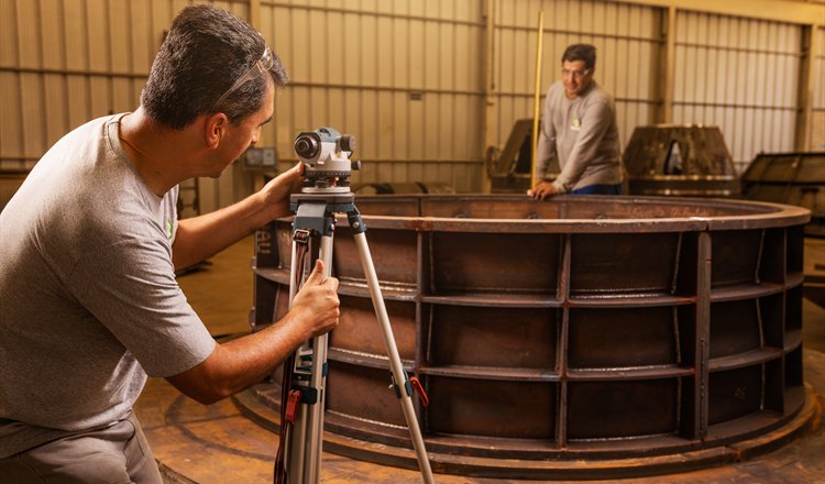 Hacker technicians surveying a fabricated stay ring with an optical level